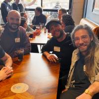 Four alumni smile at booth